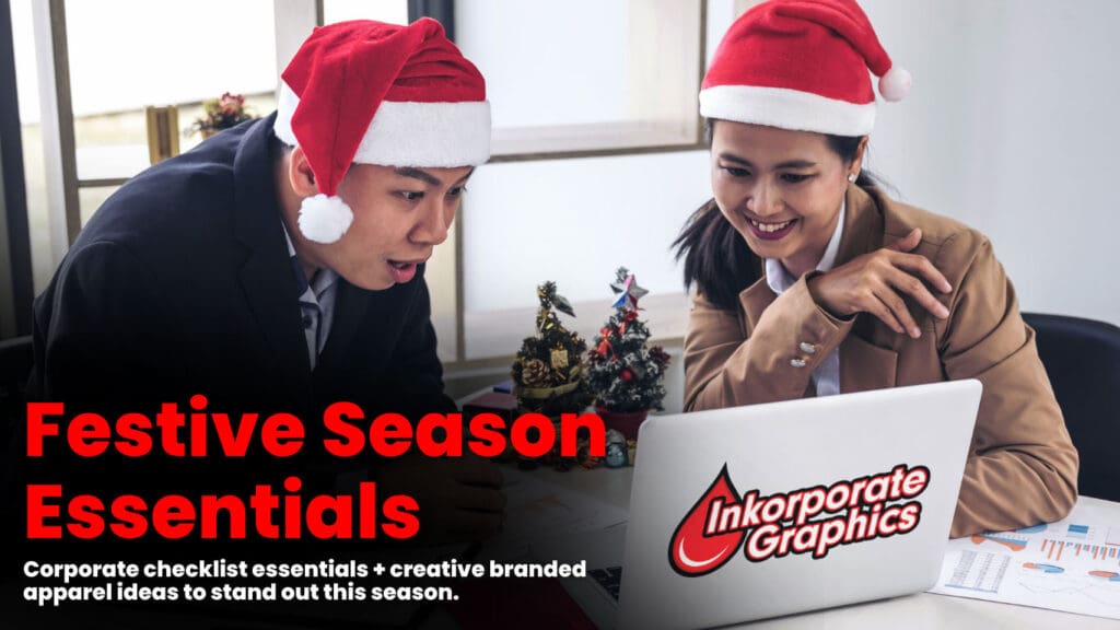 Two office professionals-wearing Santa hats reviewing holiday branding plans on a laptop featuring the Inkorporate Graphics logo, representing corporate festive season apparel and checklist essentials
